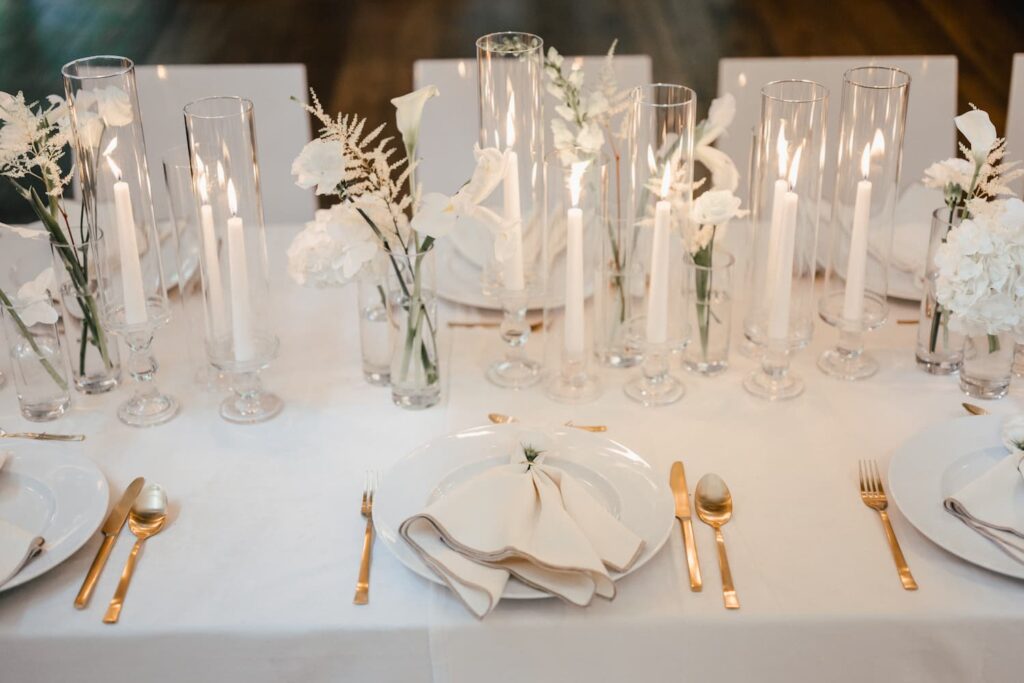 Weiße Tischdekoration mit Glasgefäßen, Blüten und Kerzen