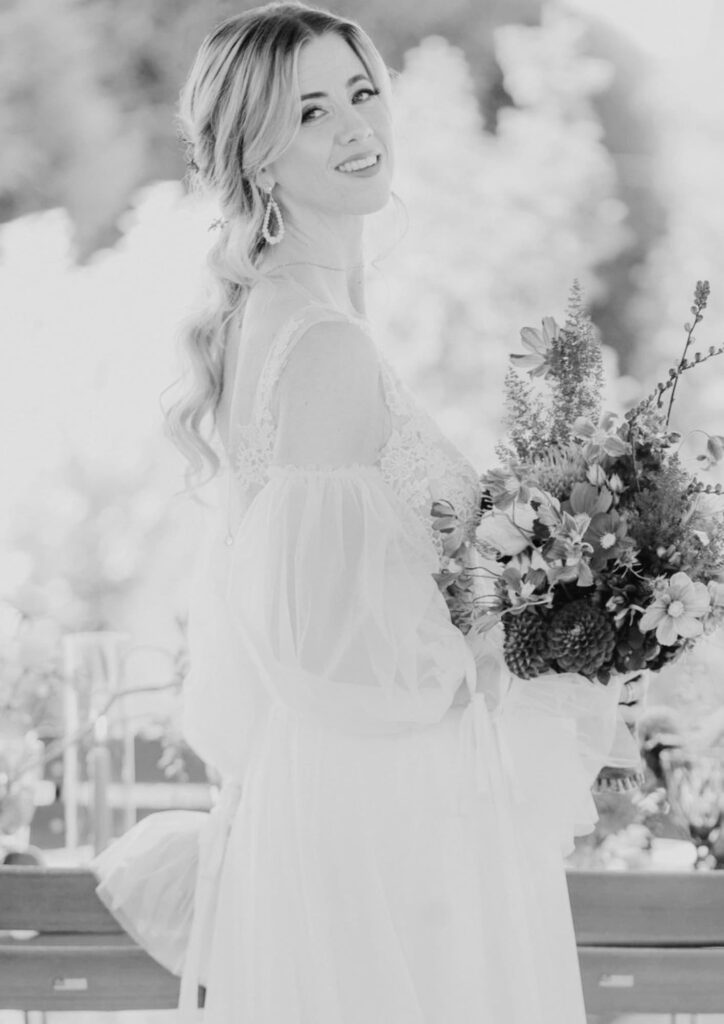 Lächelnde Braut im Hochzeitskleid mit einem üppigen Brautstrauß