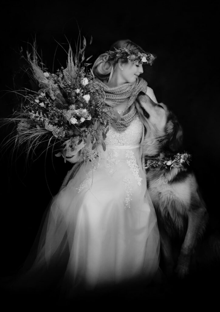 Braut mit Brautstrauß und Hund mit floralem Schmuck